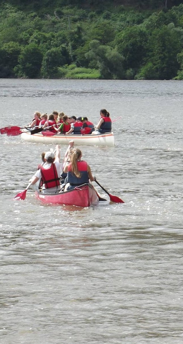 A group paddles together in canoes on a river